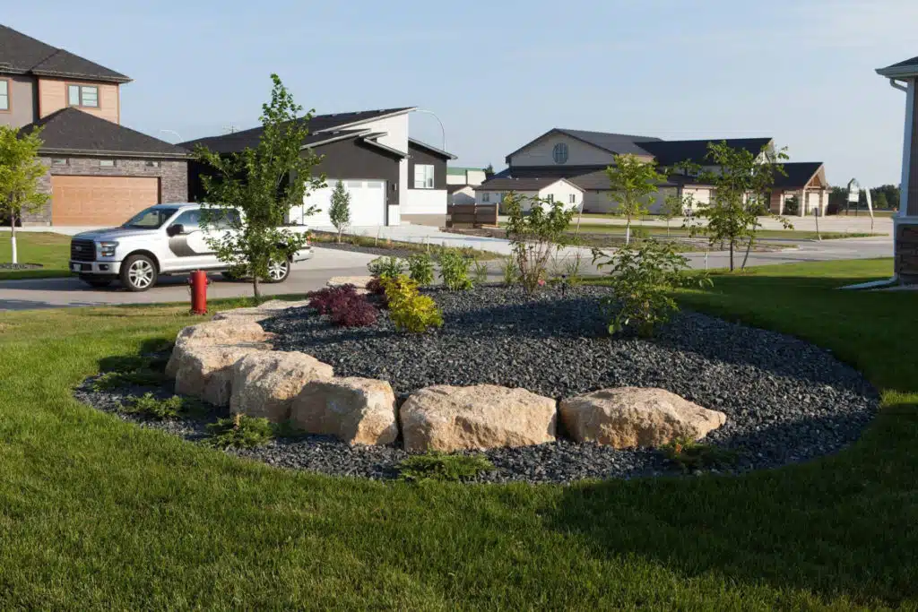 Residential front yard with rock garden, shrubs, and black gravel