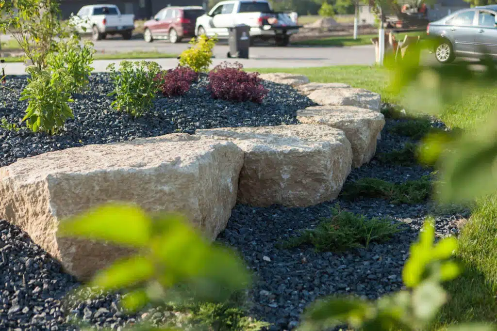Landscaping with large boulders, dark gravel, and green plants
