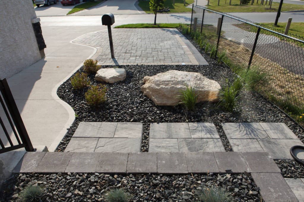 Rock features a landscaped stone pathway, and a driveway, for a Winnipeg residential home.