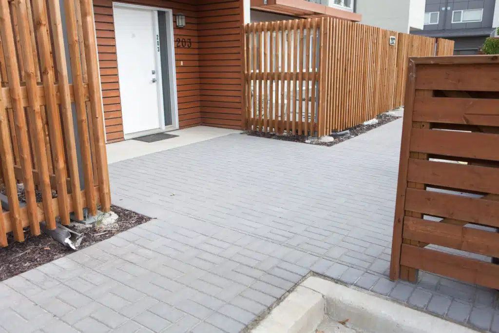 A brick path leads to the front door (203) of a modern townhouse with a wood fence.