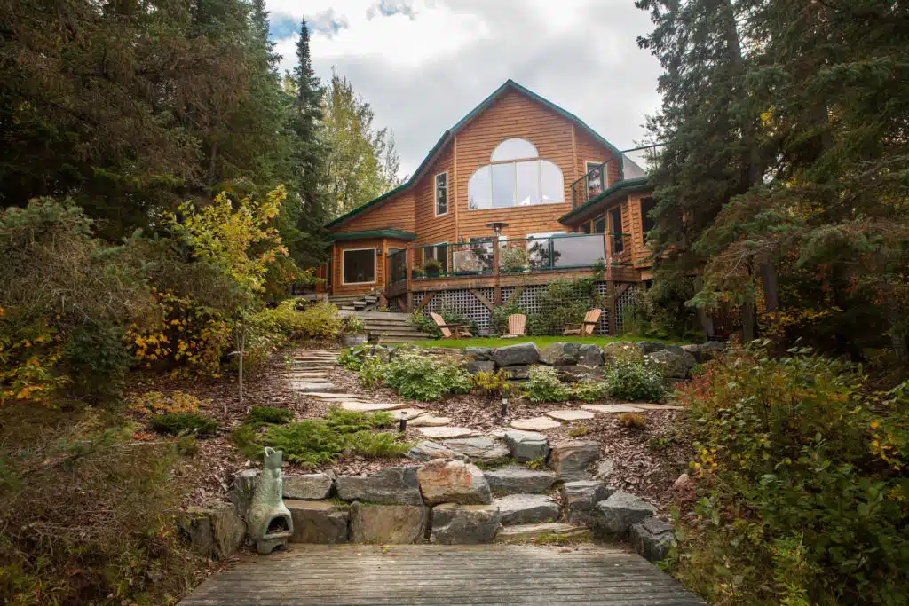 Multiple stone retaining walls and planting beds in front of wooden cabin.