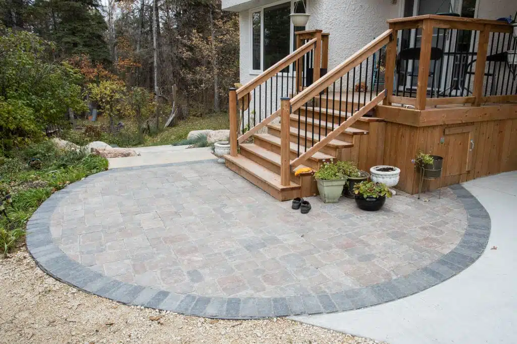 Circular stone patio with stairs leading to a raised wooden deck with railing