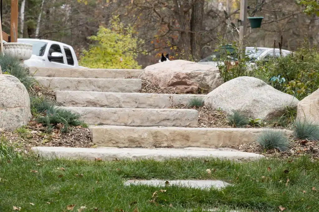 Stone steps bordered by rocks lead to a lawn