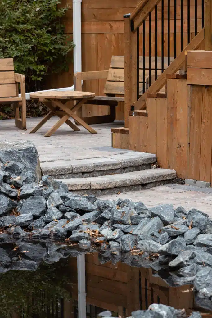 Backyard patio with stone landscaping, wood furniture, and deck steps