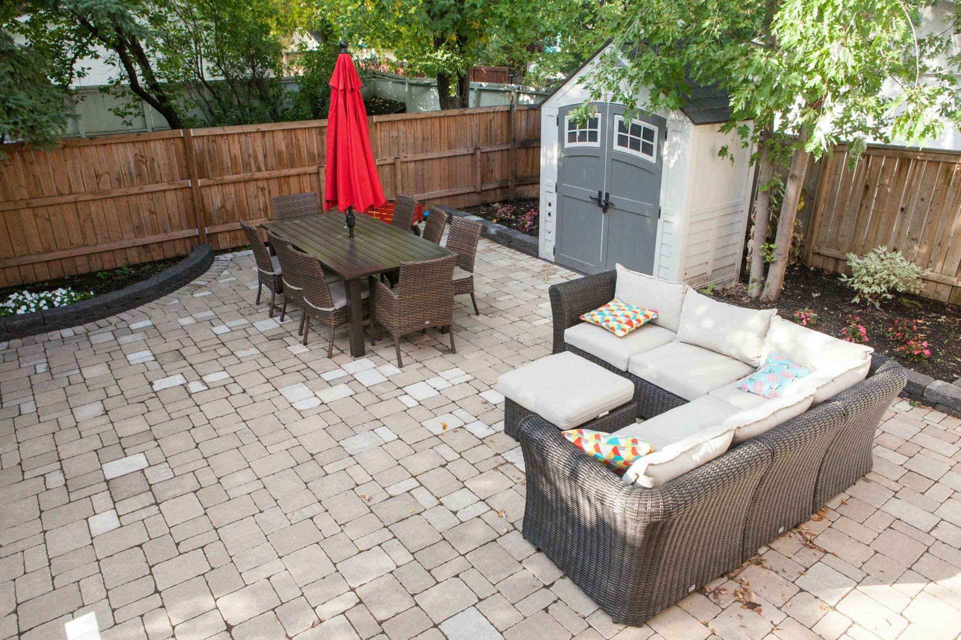 Brick patio and planting beds with outdoor furniture.