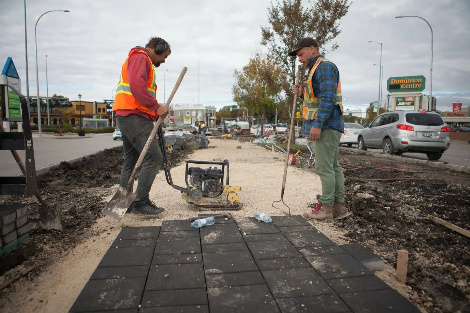 Two workers flattening gravel for commercial brick walkway