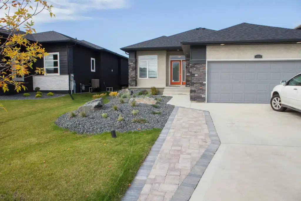 A single-story home with a stone walkway leading to the orange front door