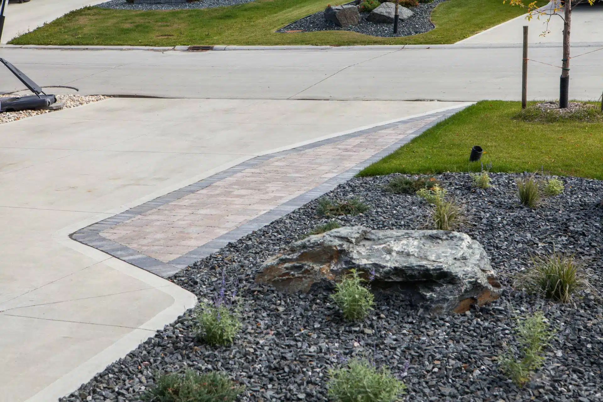 Driveway and rock featured planting bed in suburban front yard.