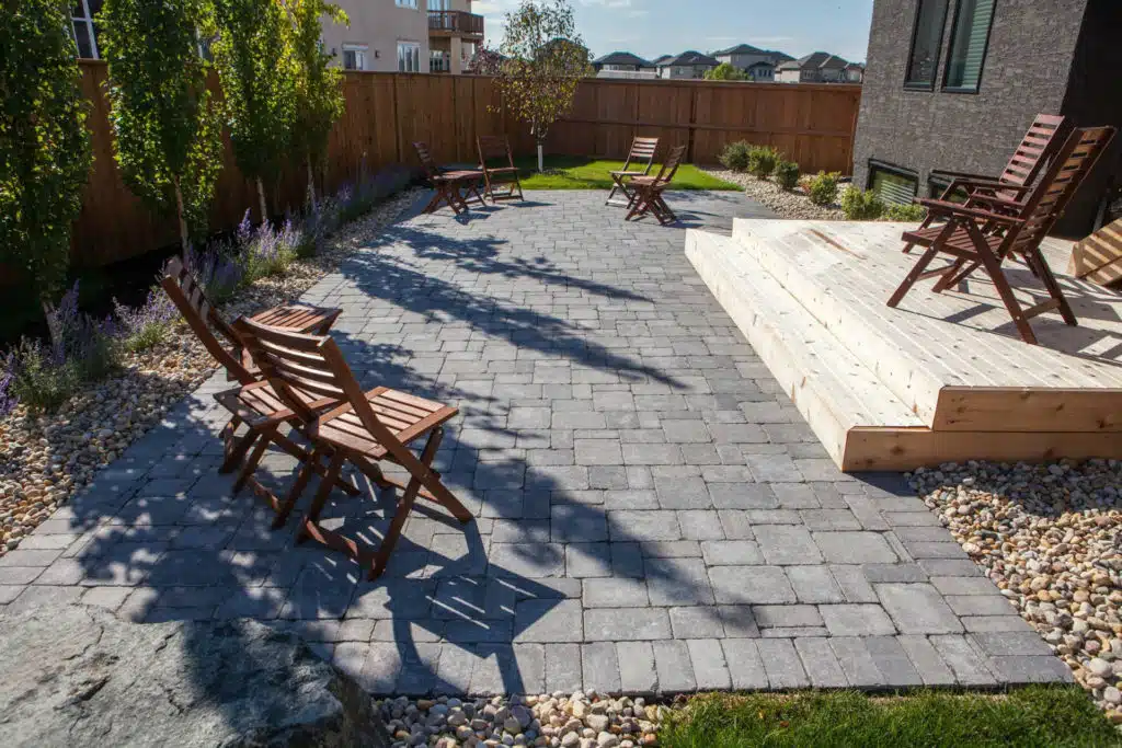 Backyard patio with stone pavers, wooden deck, and several chairs