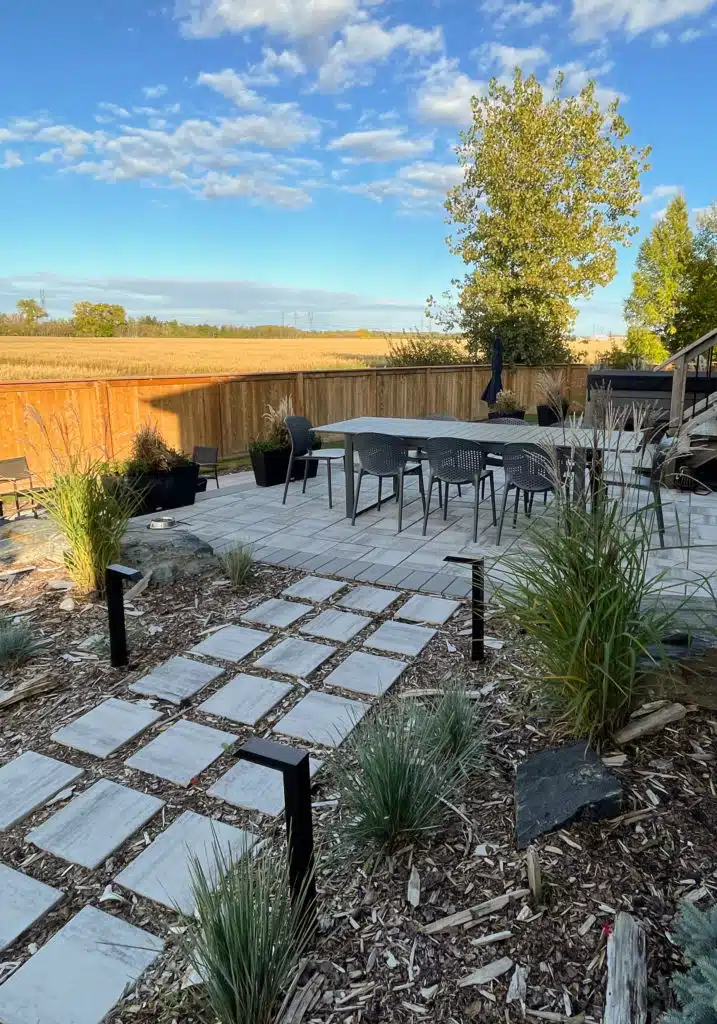 A backyard patio with a dining set, stone walkway, and landscaping