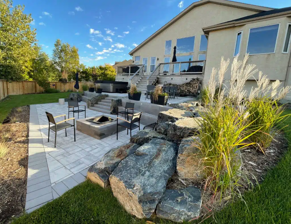 landscaped backyard, with stone patio & fire pit, elevated deck, rock features