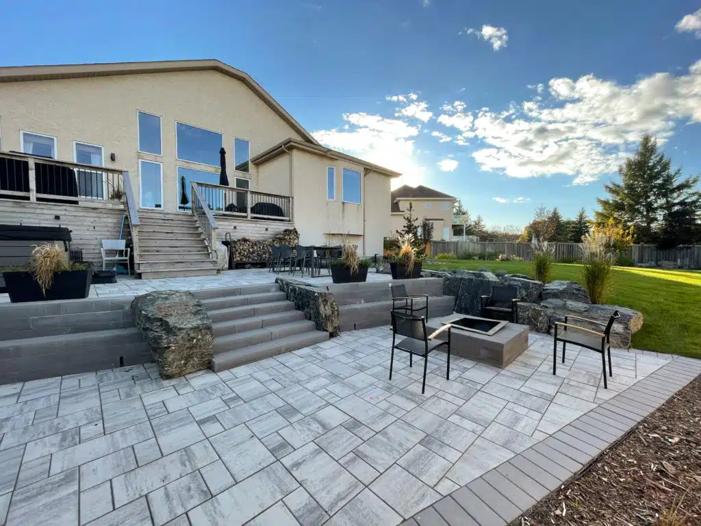 Multi-level backyard patio with stone fire pit, dining area and seating