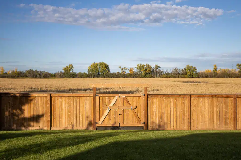 Backyard with wooden fence and gate overlooking a wheat field