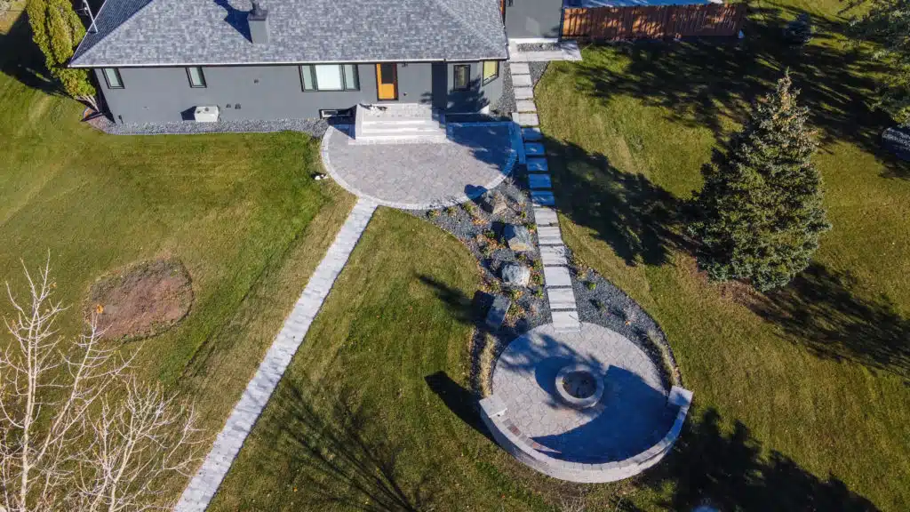 Aerial view of a backyard with a patio, fire pit, and stone pathways