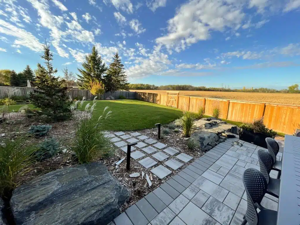 Backyard stone patio and walkway, with lighting, and natural landscaping features.