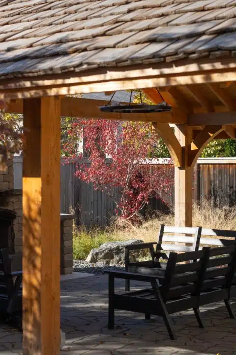 Covered patio with wood beams, furniture, and autumn foliage