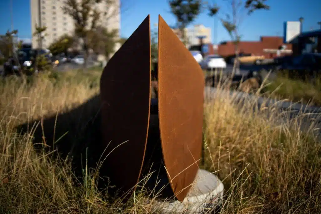A rusty, abstract metal sculpture in a grassy field