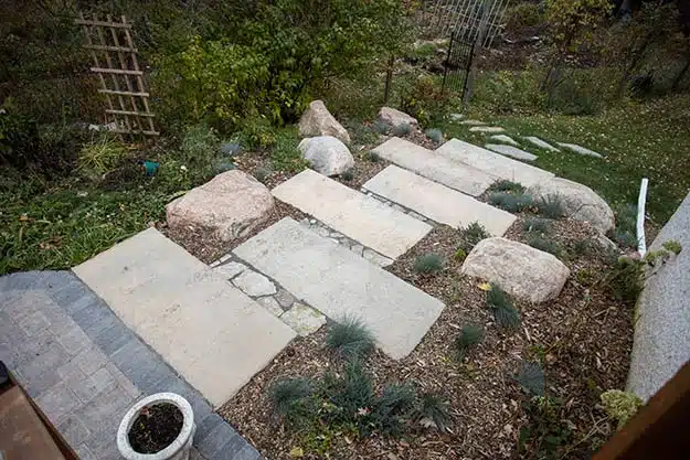 Stone slab steps surrounded by landscaping boulders and wood chips