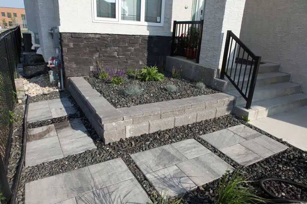 Front yard landscaping with stone planter, rock garden, and pavers