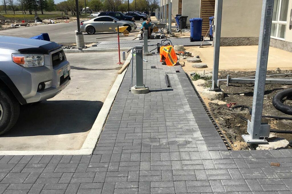 A person installs a parking meter on a new brick walkway in front of a building