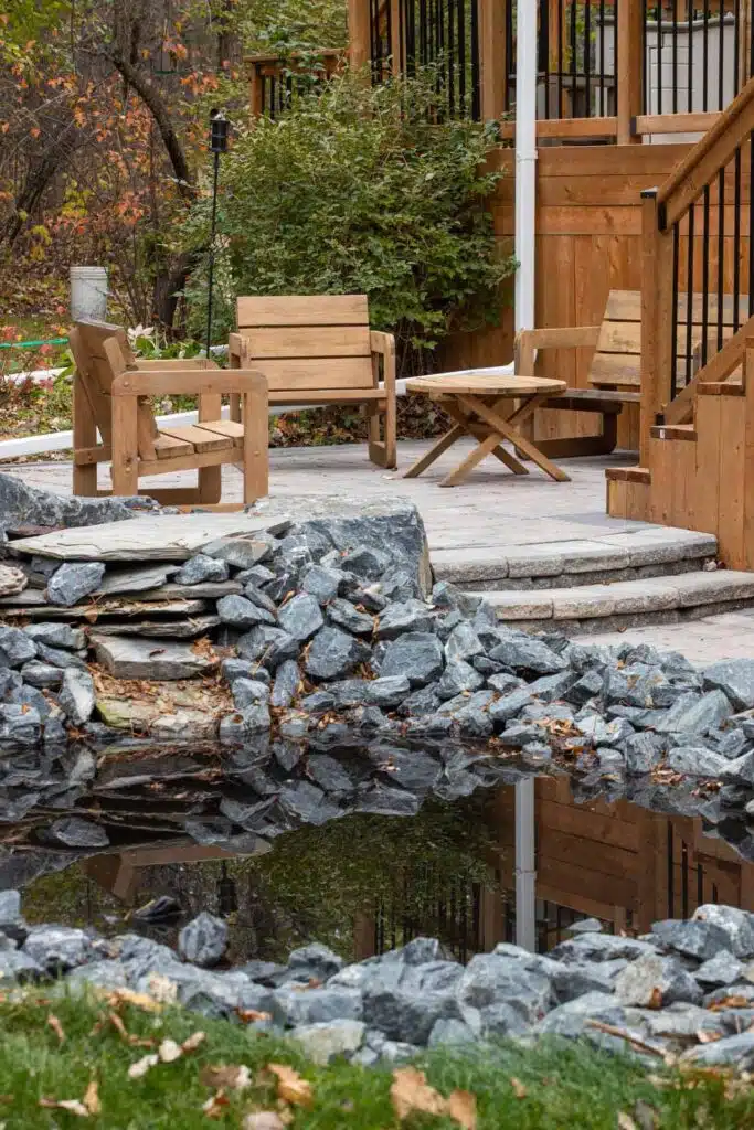 Backyard patio with wooden furniture, pond, rock garden and raised wooden deck
