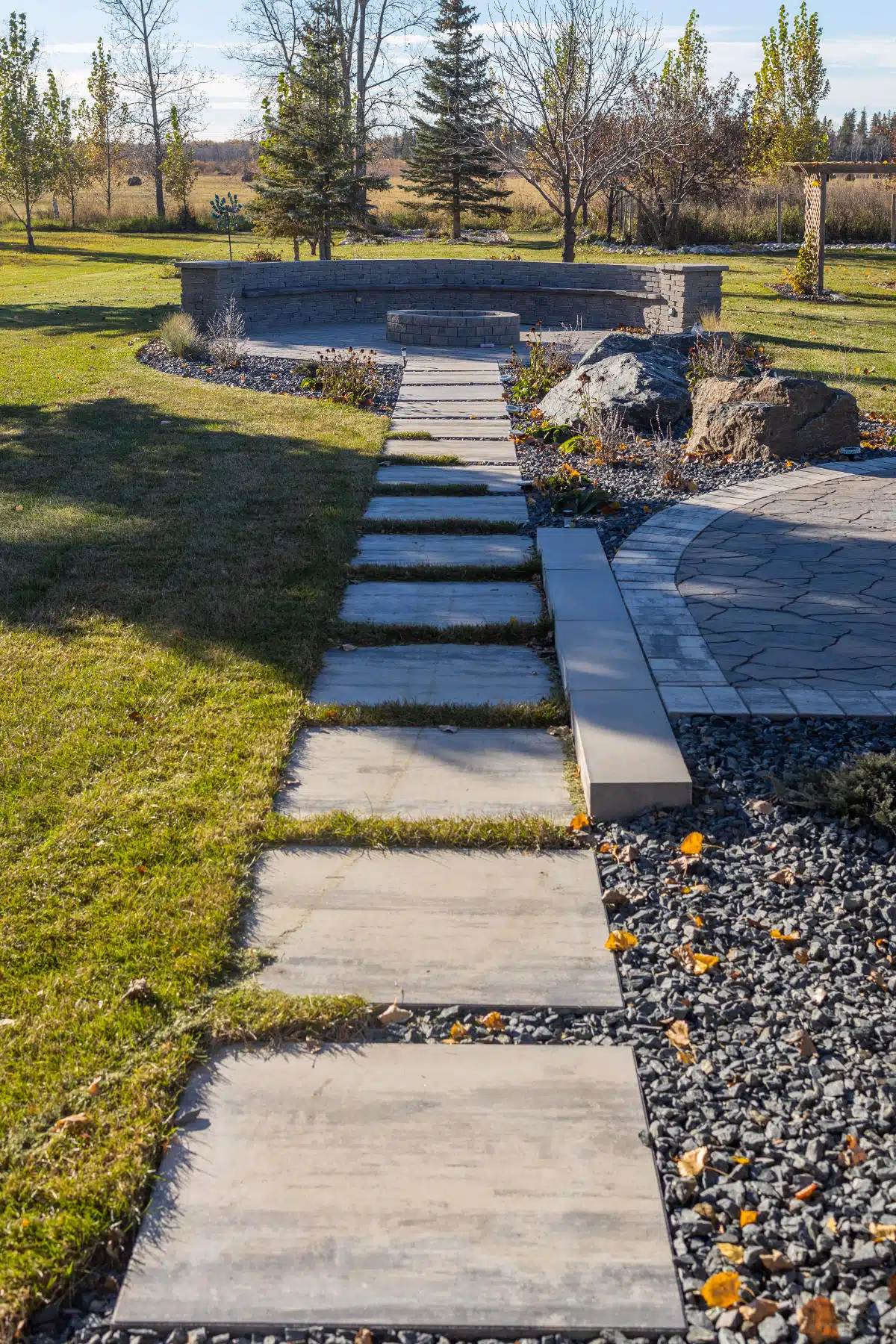 Stone pathway leading to stone fire pit in backyard.
