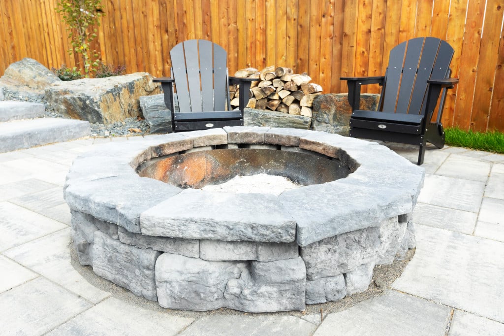 Stone fire pit and a brick patio, with outdoor chairs.