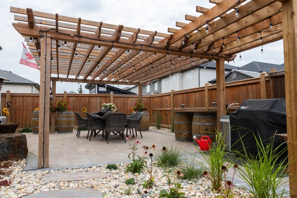 Backyard patio with pergola, string lights, dining table, and barbecue grill.