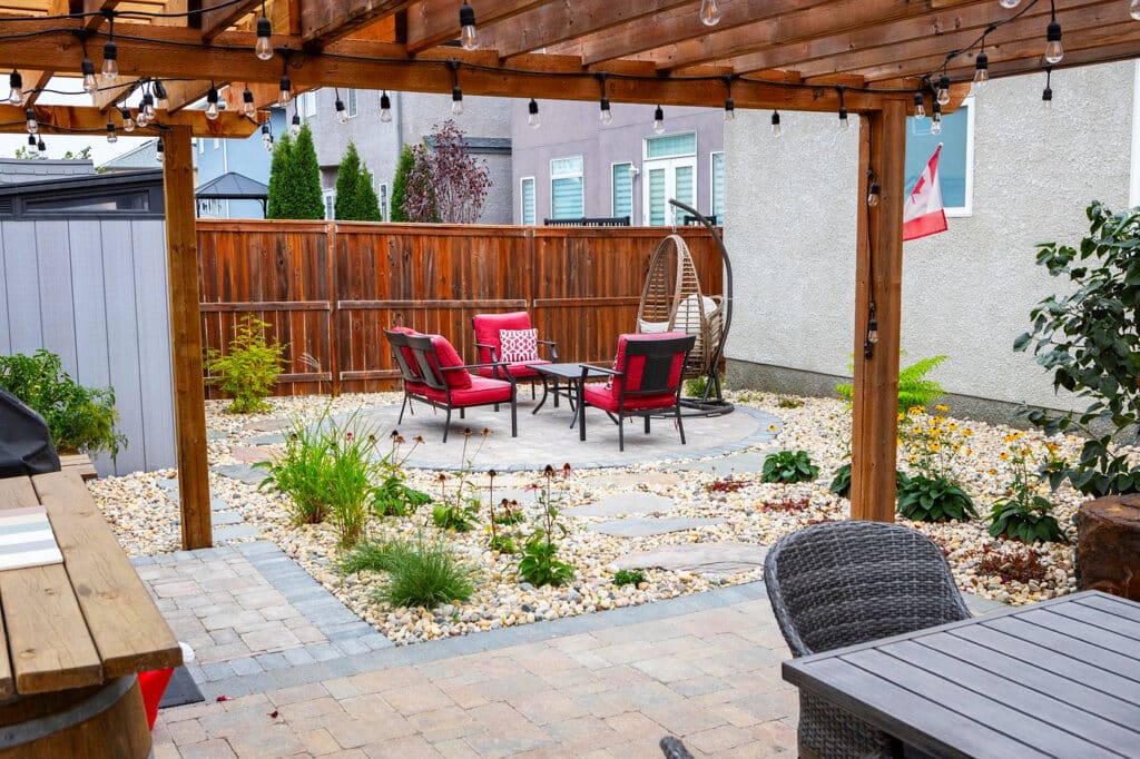 Backyard patio with pergola, string lights, dining table, and barbecue grill.