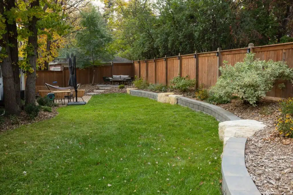 Landscaped yard with curved stone wall and lush seating areas.