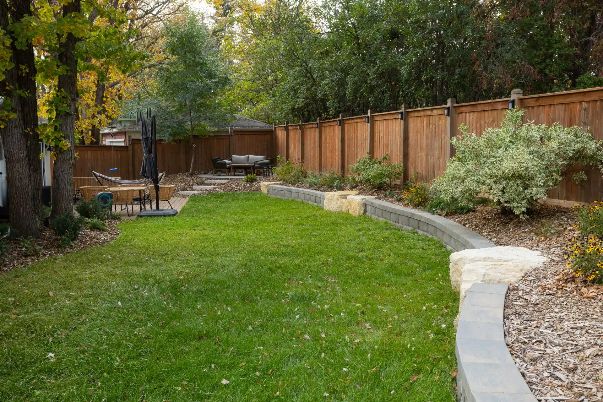 Landscaped yard with curved stone wall and lush seating areas.