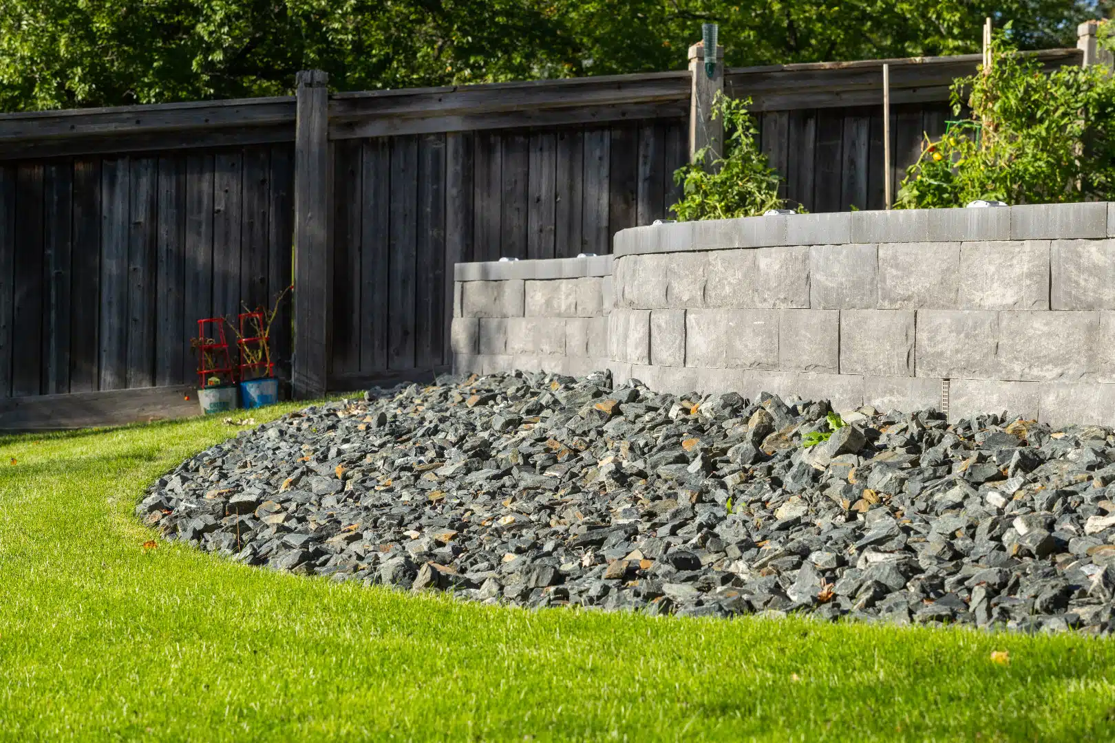 Raised stone retaining wall with decorative rock bed and lawn.