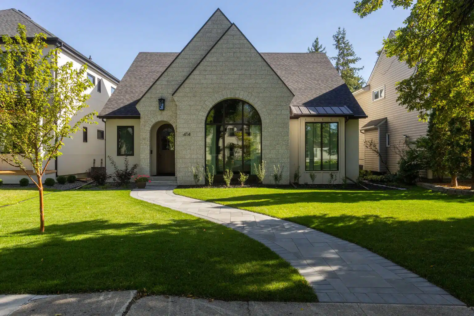 Modern front yard with curved paver walkway and lush lawn