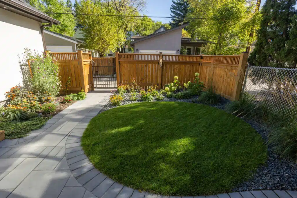 Backyard patio with curved grass, pavers, and cedar fence