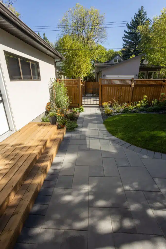 Backyard paver patio with wood steps and garden beds