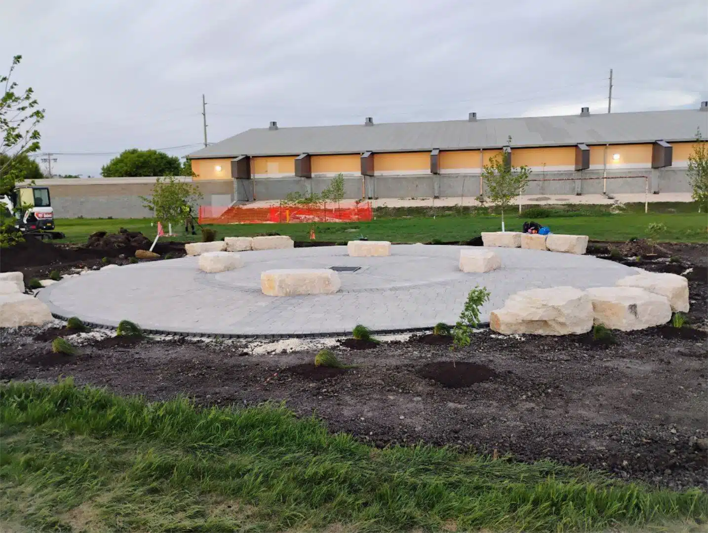 Circular paver patio under construction with limestone seating and new plantings