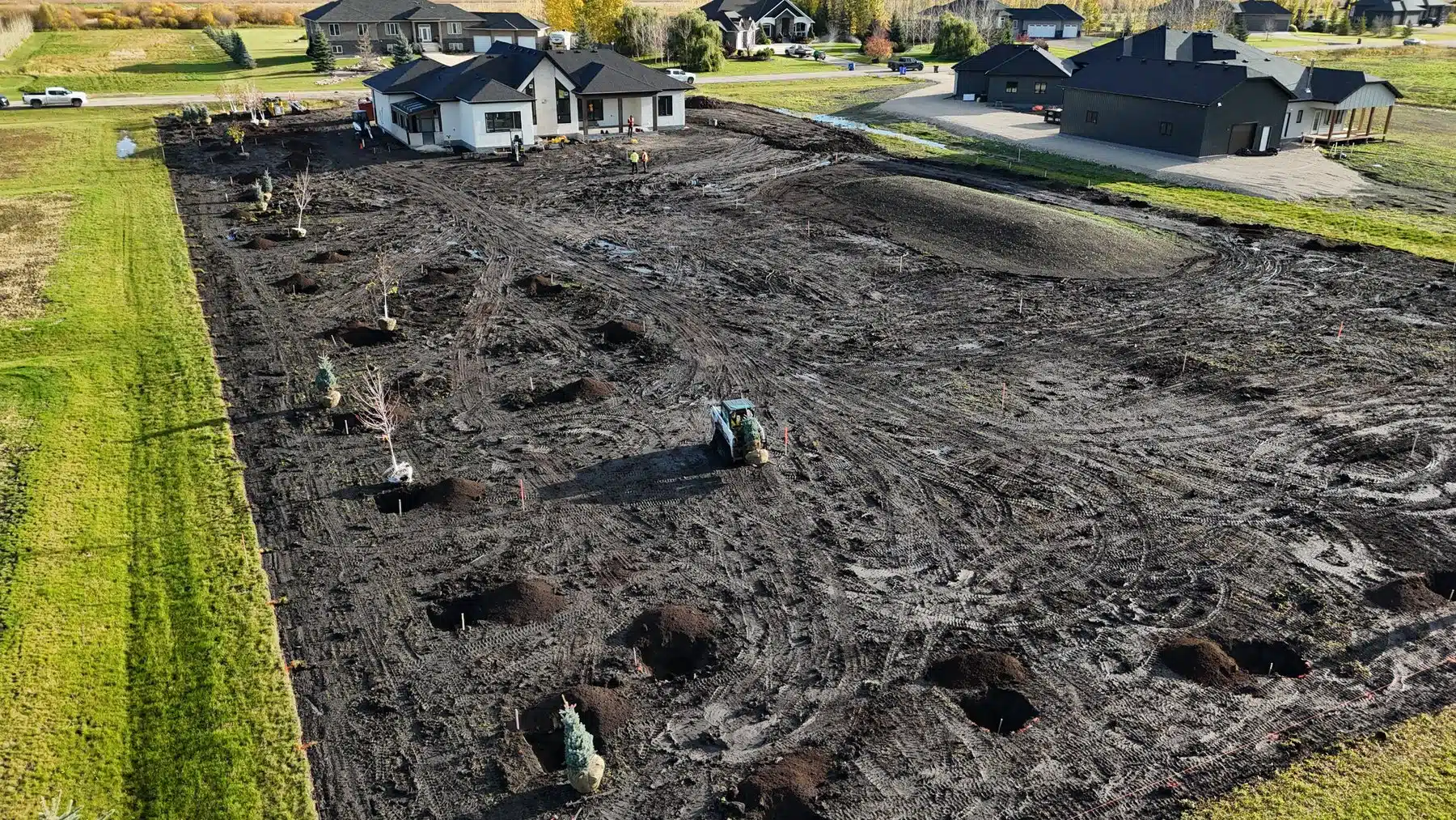Large property during landscape preparation with planting locations and site grading visible.