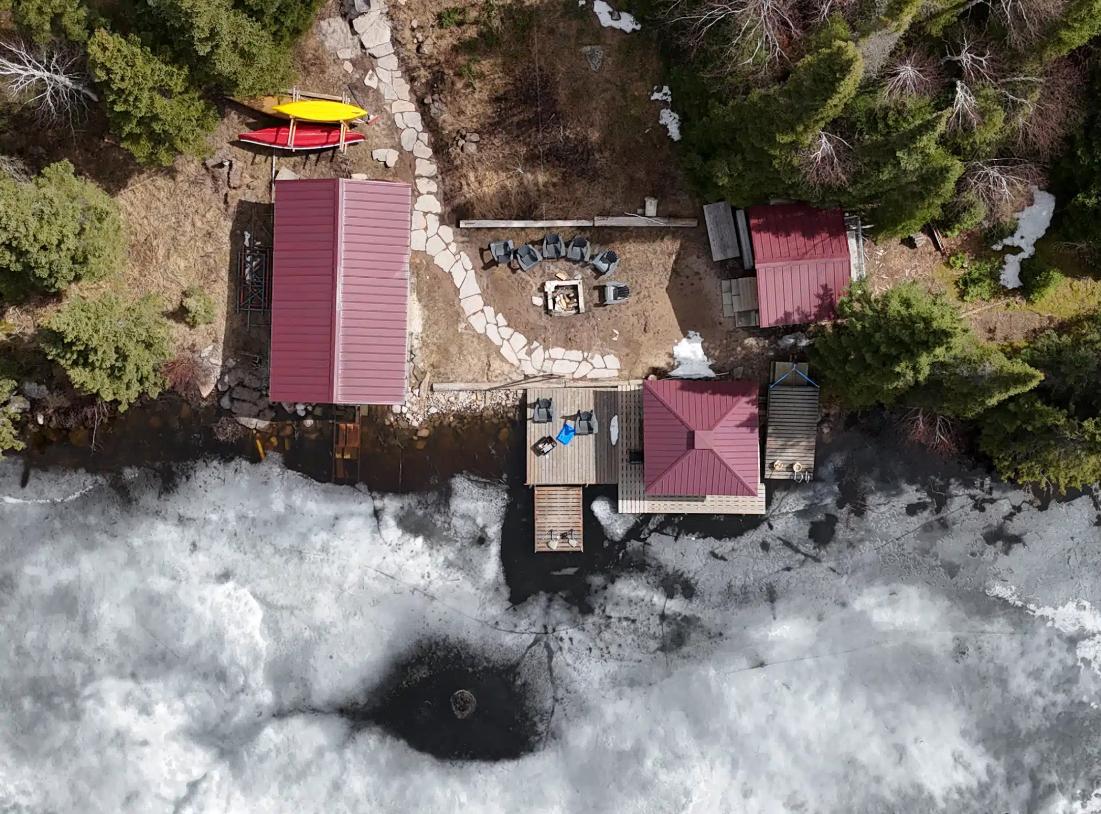 Aerial view of a cabin in winter, with a new completed stone path.